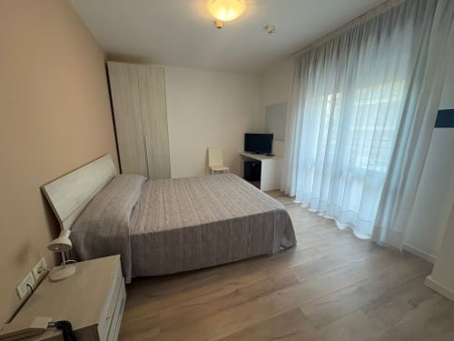 Spacious family room at Hotel Panorama Lido di Jesolo with double bed, flat-screen TV, wardrobe, and sheer curtains