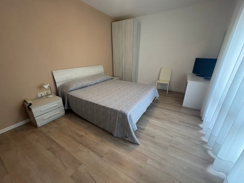 Modern family bedroom at Hotel Panorama Lido di Jesolo with double bed, wardrobe, TV, and wooden flooring