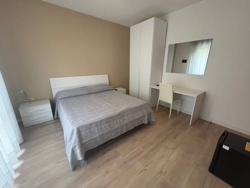 Modern hotel bedroom at Hotel Panorama Lido di Jesolo with queen bed, white wardrobe, desk, and mirror