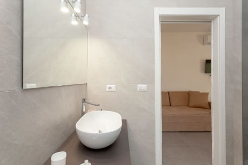 Modern bathroom at Le Dune Relax hotel in San Teodoro with round white sink, mirror, and view to bedroom