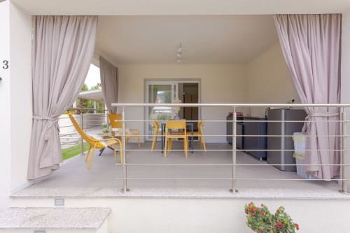 Modern terrace at Le Dune Relax hotel in San Teodoro with yellow chairs, pink curtains, and pool view