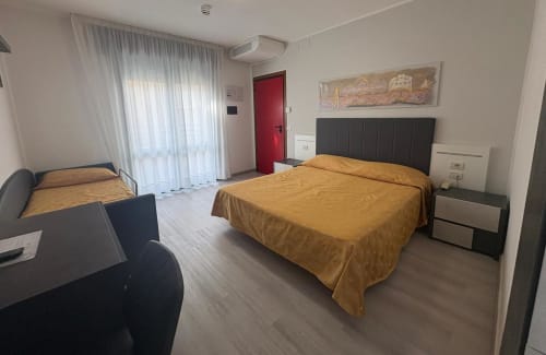 Spacious quadruple room at Hotel Panorama Lido di Jesolo with twin beds, golden bedding, balcony, and modern amenities