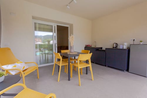 Quadrupla room at Le Dune Relax with yellow chairs, dining table, and pool view in San Teodoro