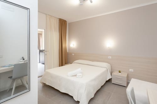 Modern bedroom at Le Dune Relax hotel in San Teodoro with queen bed, wooden headboard, and garden views