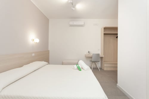 Modern hotel bedroom at Le Dune Relax in San Teodoro with queen bed, desk, wardrobe, and air conditioning