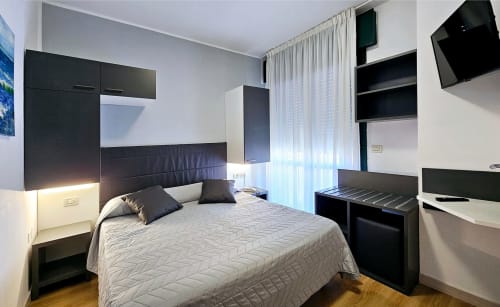 Modern hotel bedroom at Hotel Panorama Lido di Jesolo with double bed, black headboard, flat-screen TV, and contemporary