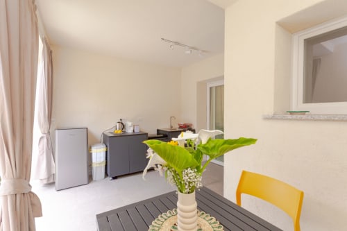 Le Dune Relax hotel room in San Teodoro with kitchenette, yellow chair, and white flowers on table