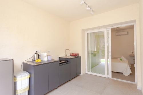 Modern kitchenette with dark cabinetry and sliding glass doors leading to bedroom at Le Dune Relax, San Teodoro