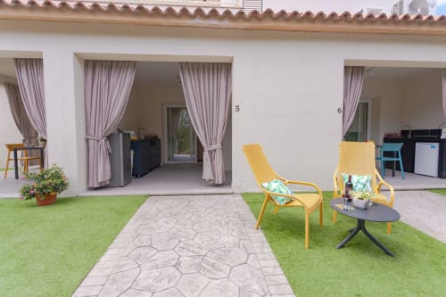 Garden view patio at Le Dune Relax hotel in San Teodoro with yellow lounge chairs and stone pathway