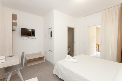 Modern hotel room at Le Dune Relax in San Teodoro with bed, TV, desk, and garden view