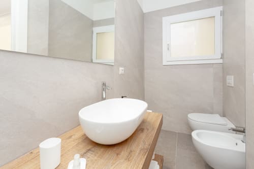 Modern bathroom with round white sink, wooden vanity, and bidet at Le Dune Relax hotel in San Teodoro