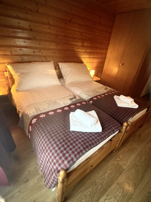 Acogedora habitación de madera en Hôtel La Tour d'Aï Leysin con cama doble, almohadas blancas y ropa de cama estilo alpino