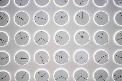 Plusieurs horloges murales illuminées affichant des heures différentes à l'Appart'Hôtel Résidence de Tourisme de Cholet