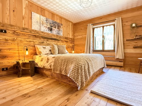 Accogliente camera da letto in legno nell'appartamento di montagna ad Auronzo di Cadore con letto matrimoniale, camino e vista sulle Alpi