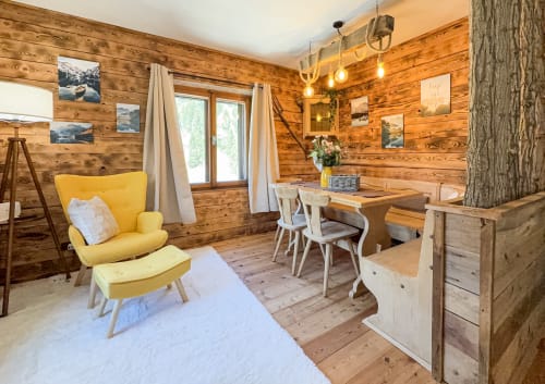 Accogliente appartamento con rivestimenti in legno ad Auronzo di Cadore, poltrona gialla, tavolo da pranzo e vista sulle montagne