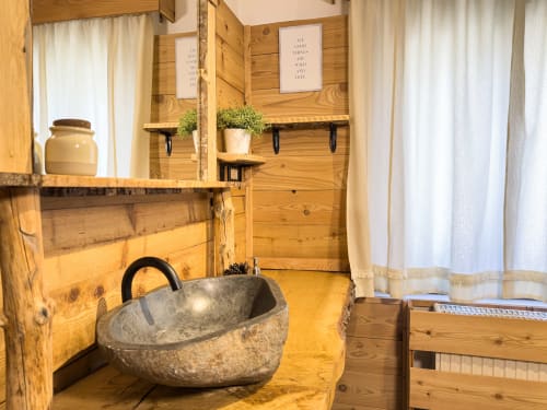 Bagno rustico in legno con lavabo in pietra e scaffalature presso l'appartamento Mountains Properties ad Auronzo di Cadore