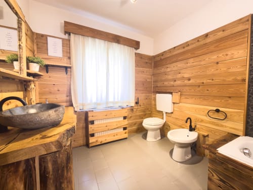 Rustico bagno in legno nell'appartamento alpino di Mountains Properties, Auronzo di Cadore, con toilette, lavabo, vasca e
