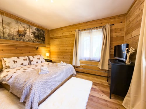 Accogliente camera da letto in legno a Auronzo di Cadore con vista montagna, letto matrimoniale, TV e comfort moderni