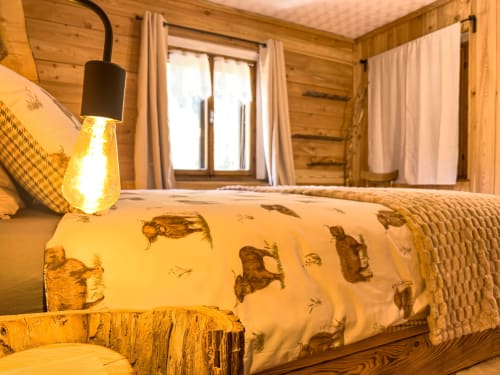 Accogliente camera alpina ad Auronzo di Cadore con pareti in legno, biancheria trapuntata, caldo lampadario a sospensione e vista montagna