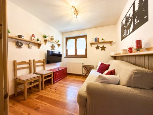 Accogliente soggiorno con divano beige, sedie in legno, TV e vista sulle montagne a Mountains Properties ad Auronzo di Cadore