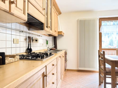 Cucina moderna in Mountains Properties Auronzo di Cadore con fornello a gas, mobili in legno, rivestimento in piastrelle bianche