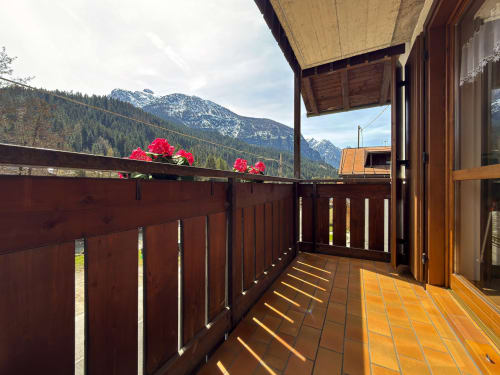 Balcone di montagna con fiori rossi, mattonelle in terracotta e vista sulle Dolomiti innevate ad Auronzo di Cadore