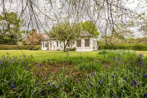 Sleeping Betty cottage in Comrie with purple irises blooming in the garden, white cottage exterior visible across manicured