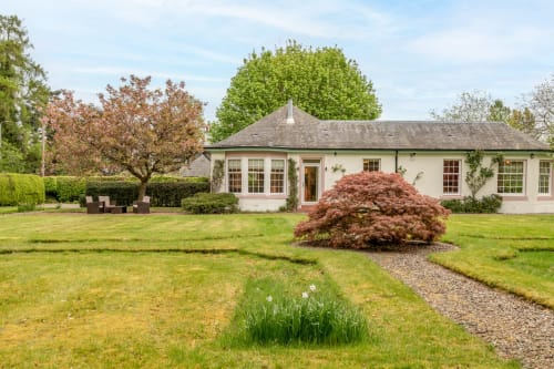 Sleeping Betty cottage Crossloan in Comrie with manicured gardens, red maple tree, and stone pathway leading to the detached