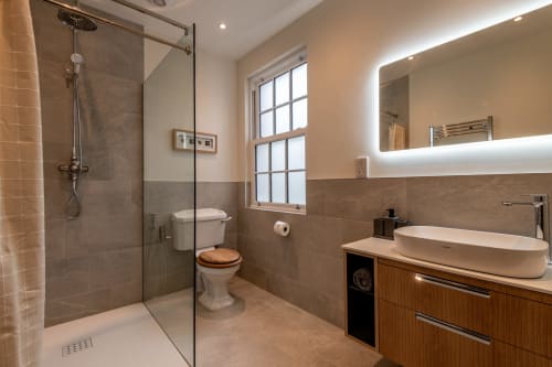 Modern bathroom in Sleeping Betty cottage, Comrie featuring walk-in shower, wooden vanity, and heated mirror