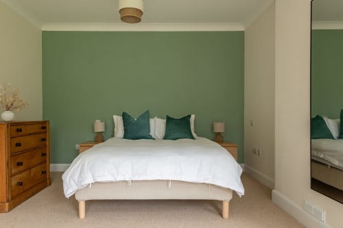Crossloan cottage bedroom at Sleeping Betty, Comrie with green accent wall, white duvet, teal pillows, wooden furniture and