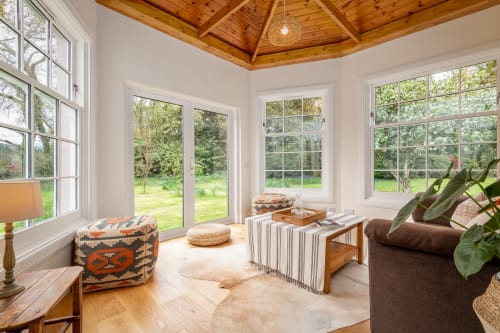 Bright sunroom at Sleeping Betty cottage in Comrie with wooden ceiling, garden views, comfortable seating, and natural light