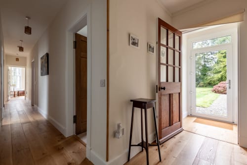 Bright hallway at Sleeping Betty cottage in Comrie with hardwood floors, garden view doors, and wooden staircase.