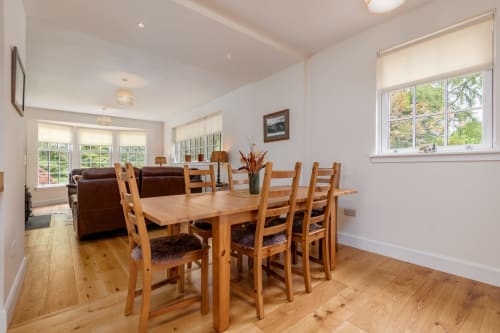 Dining area with wooden table and chairs in Crossloan cottage at Sleeping Betty, Comrie, with garden views and lounge seating