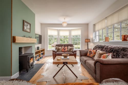Cosy Crossloan cottage living room with wood burner, garden views, brown sofas and modern amenities at Sleeping Betty, Comrie