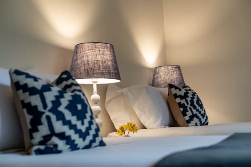 Cozy bedroom at Sleeping Betty cottage in Comrie with patterned pillows, table lamps, and white bedding