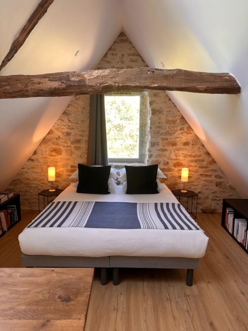 Chambre rustique sous les combles du Gîte l'Harmonie du Causse avec poutres apparentes, murs de brique et lumière naturelle