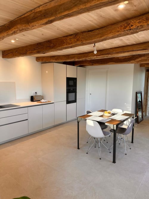 Cuisine moderne avec meubles blancs, poutres en bois et table à manger à la Gite l'Harmonie du Causse, France