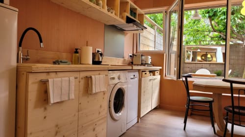 Kompakte Küche in der Tiny Lodge am Cap Ferret mit Holzmöbeln, Waschmaschine, Spüle und Fenster mit Gartenblick