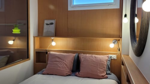 Modernes Schlafzimmer im Lodge du Cap Ferret mit Holzkopfteil, Ambientelicht, rosafarbenen Kissen und Gartenblick