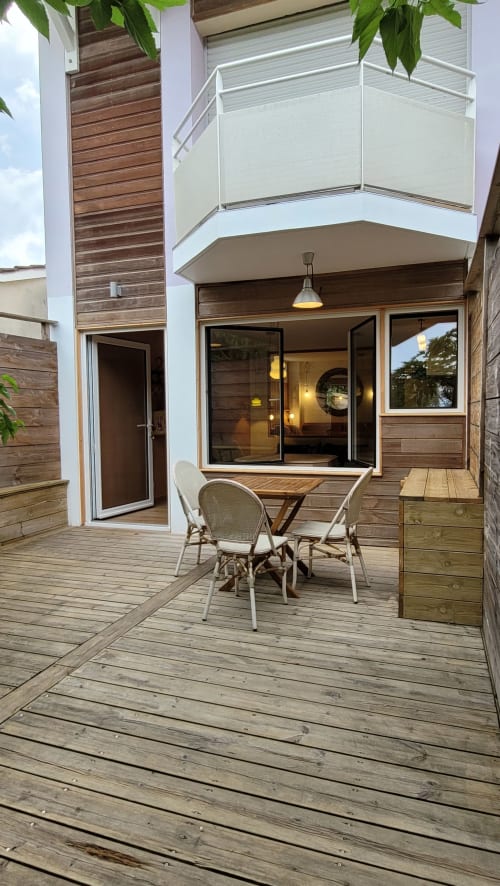 Private Terrasse der Lodge du Cap Ferret mit Holzplattform, Gartenmöbeln und modernem Apartmentinterieur