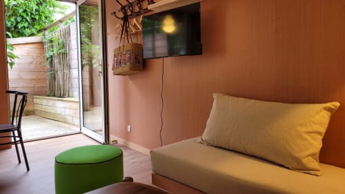 Gemütliches Studio im Le Lodge du Cap Ferret mit Terrakottawänden, beigem Sofa, gelbem Kissen, grünem Hocker und TV
