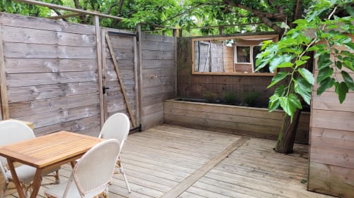 Private Terrasse vom Lodge du Cap Ferret mit Holzterrasse, Esstisch, weißen Stühlen und üppigem Grün