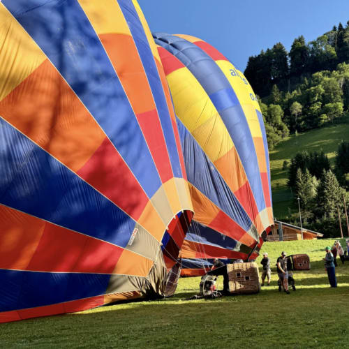 Colorful hot air balloons inflating in green valley at Chez Francine, Notre Dame de Bellecombe