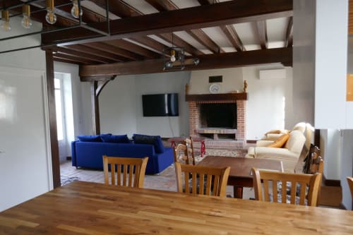 Open-plan villa gatehouse at La Jonchere with dining area, blue sofa, fireplace, and garden views in Concressault, France