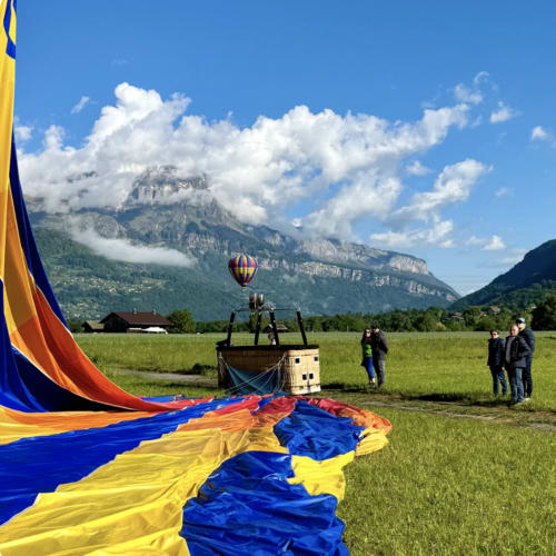 Hot air balloon launch in alpine meadow with dramatic mountain backdrop near Chez Francine