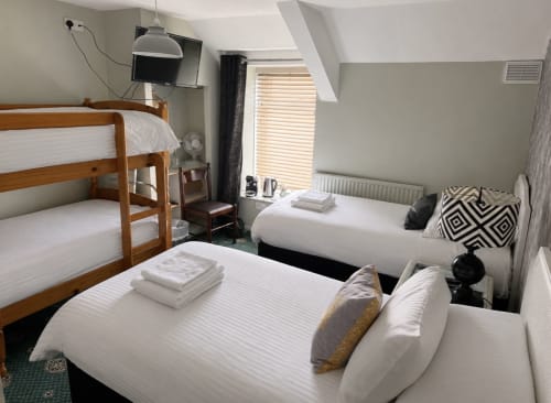 Standard Quadruple Room at Gwesty Holland Hotel with wooden bunk beds, double bed, TV, and sloped ceiling