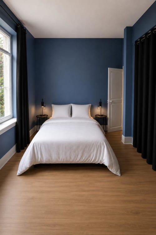 Chambre moderne à la Maison Agami avec murs bleu marine, literie blanche et parquet à Rosières aux salines
