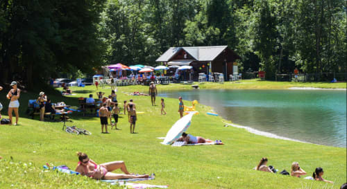 Guests enjoying lake swimming and sunbathing at Chez Francine's beach resort in Notre Dame de Bellecombe