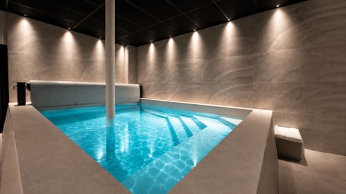 Piscine intérieure contemporaine à la Villa Avril & Spa de Sélestat avec bassin d'eau bleue et murs beiges illuminés