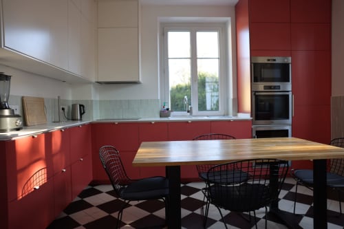 Cuisine moderne avec armoires rouges, table à manger et carrelage damier noir à Villa Avril & Spa à Sélestat